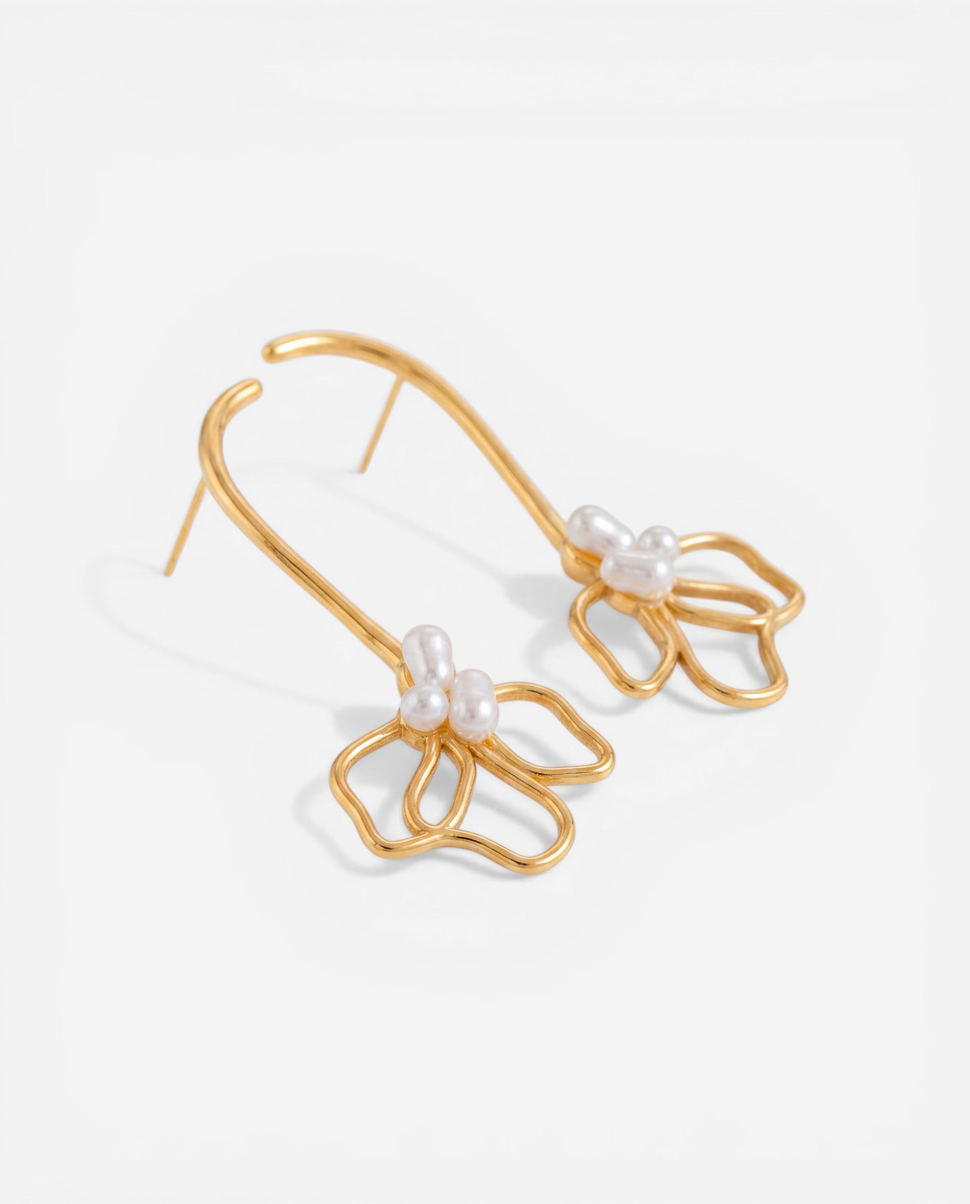Aesthetic product photography of gold floral arch earrings with pearl accents waterproof jewelry.