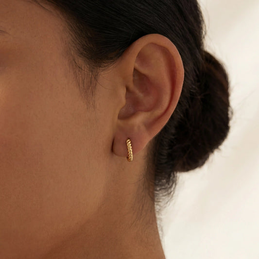 Close up of Rory gold twisted rope huggies on ear, small dainty hoop earrings for everyday, hypoallergenic stainless steel sleeper earrings.