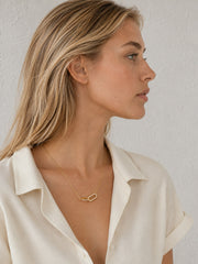 Close-up of the sculpted gold heart necklace with clear zircon accents worn at the neckline