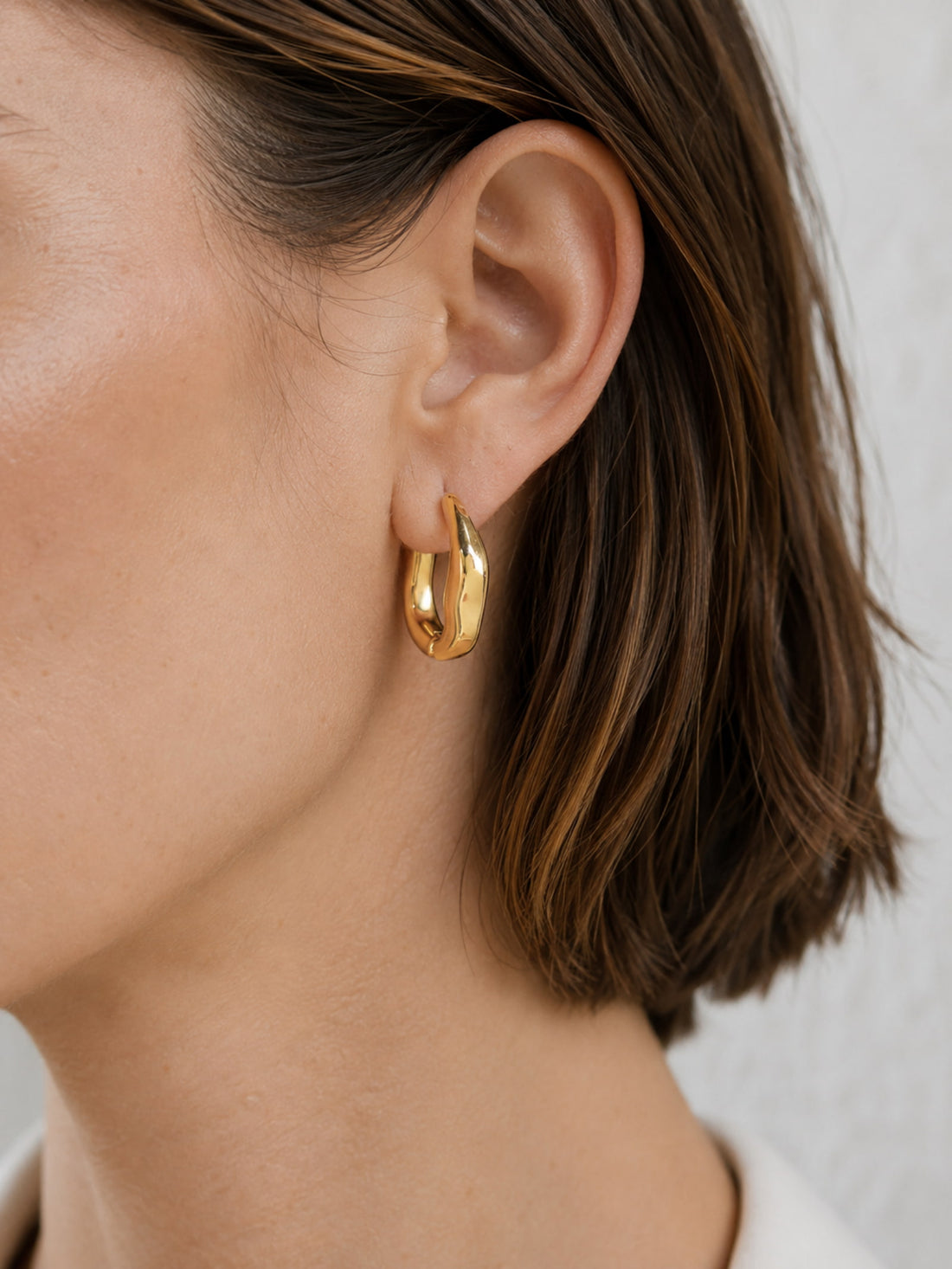 Model wearing Sculpted Wave Huggie Hoop Earrings with a simple everyday outfit