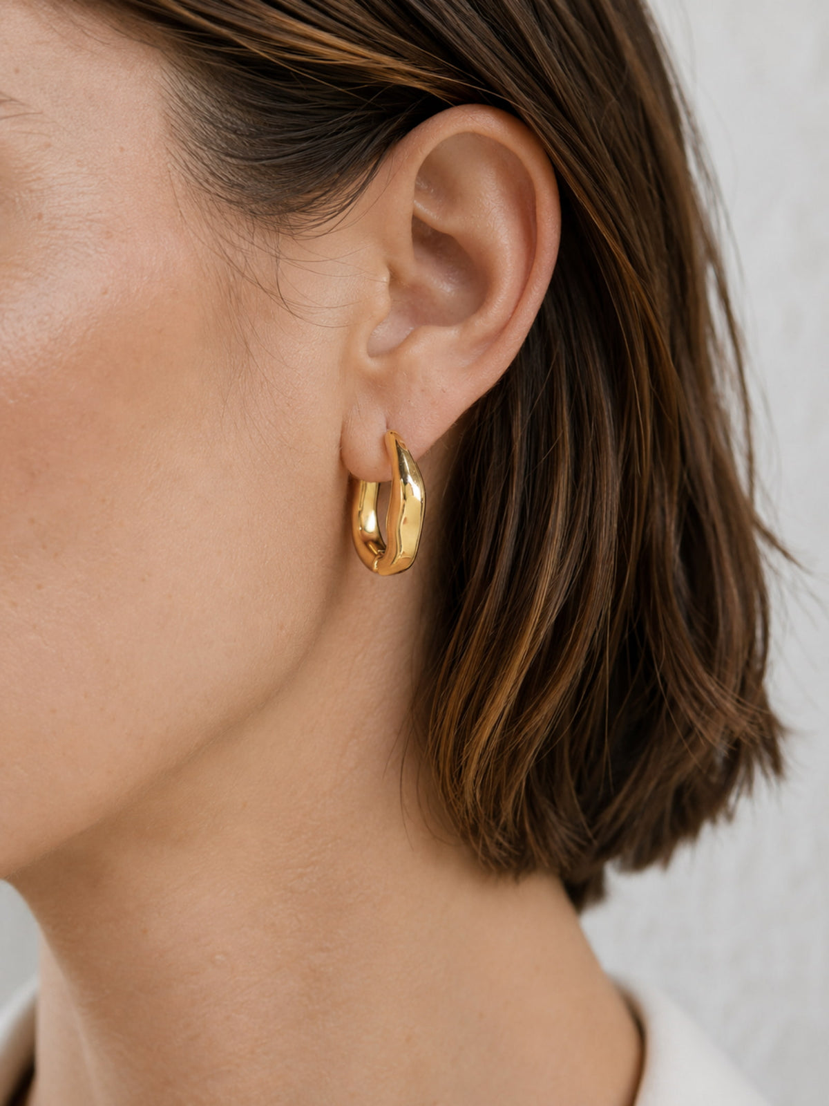 Model wearing Sculpted Wave Huggie Hoop Earrings with a simple everyday outfit