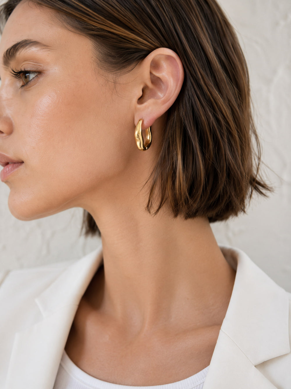 Close-up of Sculpted Wave Huggie Hoop Earrings worn by model
