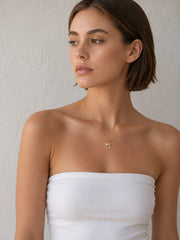 Model wearing a gold letter necklace with a clear round zircon charm