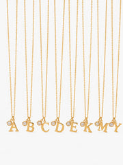 Gold initial and clear zircon pendant necklace on a clean white background