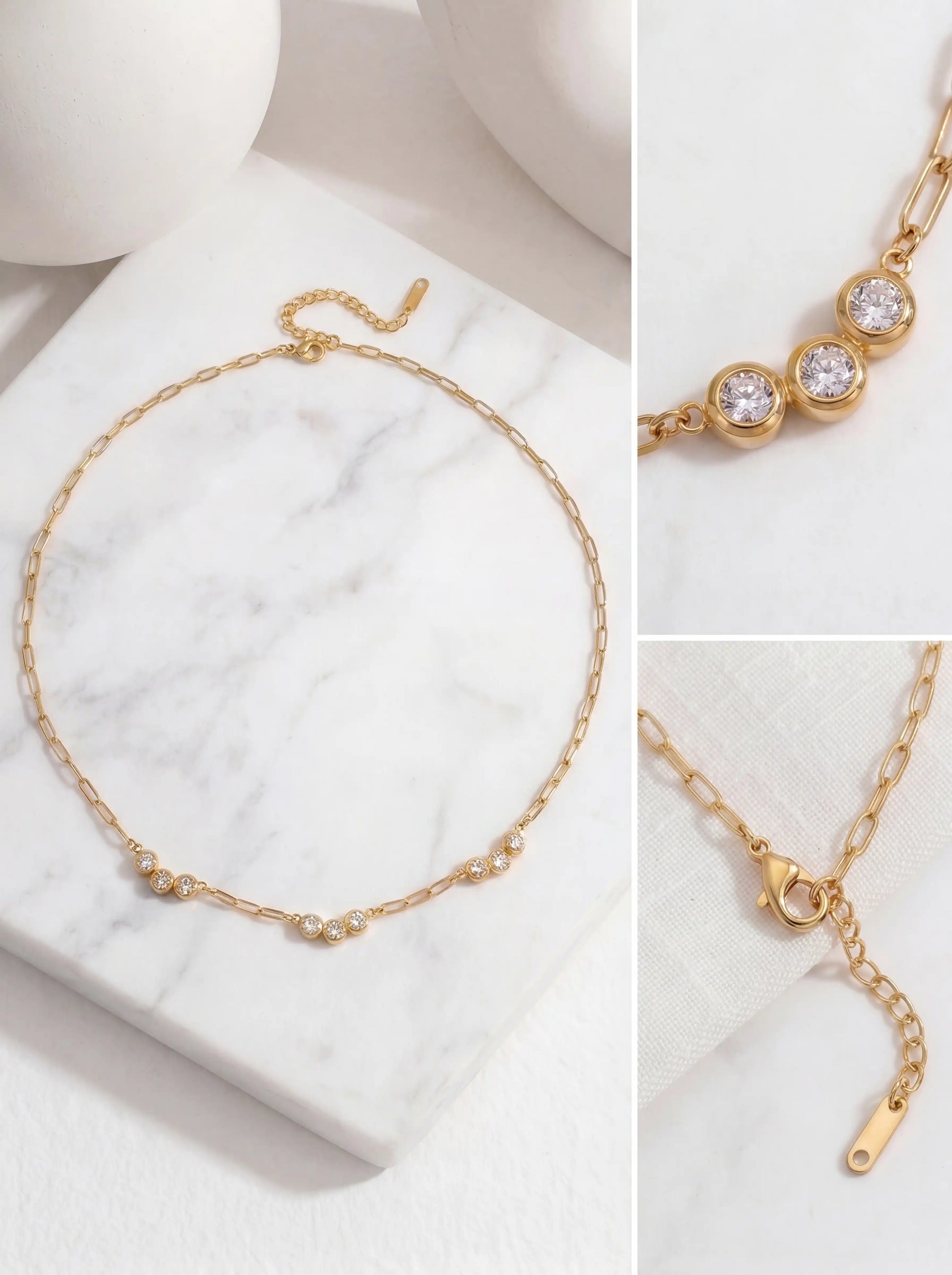 Aesthetic product photography details of gold paperclip chain and triple crystal pendant on white marble.