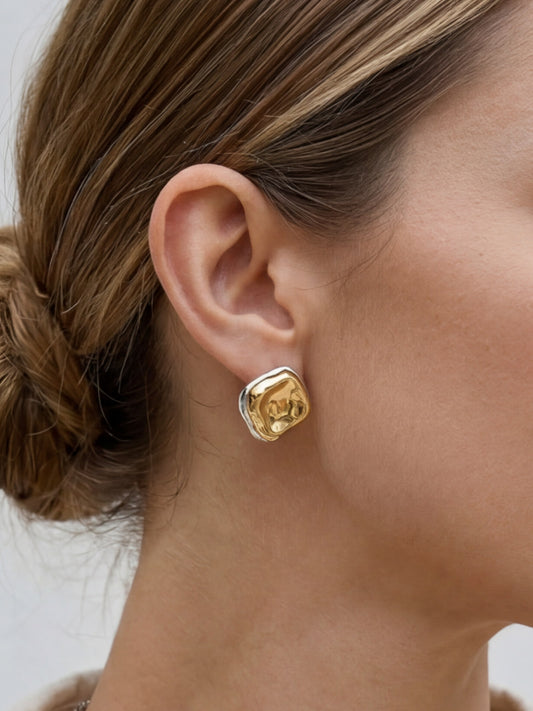 Close-up of model wearing two-tone sculptural stud earrings