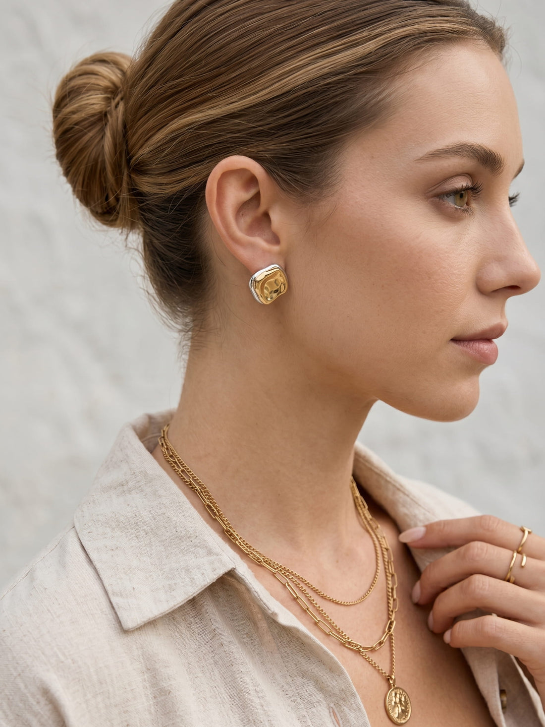 Mixed metal sculptural stud earrings styled with beige blazer