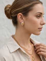 Mixed metal sculptural stud earrings styled with beige blazer