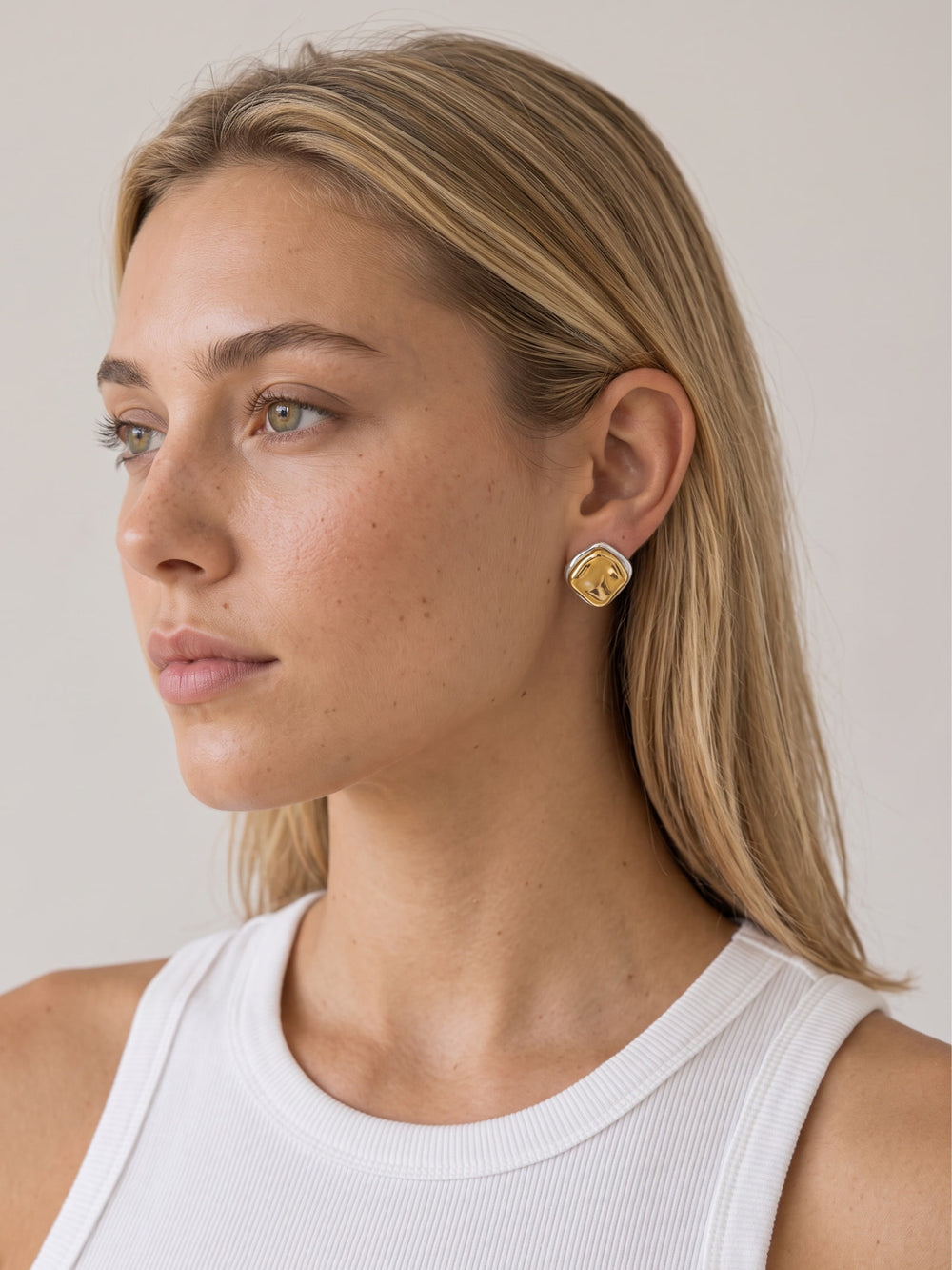 Gold and silver two-tone sculptural stud earrings styled on a model