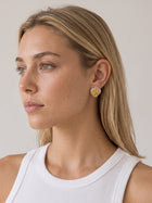 Gold and silver two-tone sculptural stud earrings styled on a model