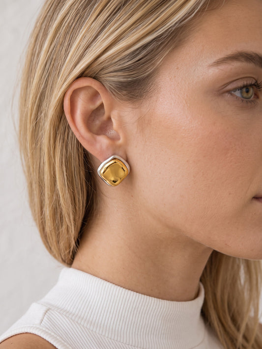 Close-up of model wearing two-tone sculptural stud earrings