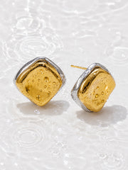 Waterproof two-tone sculptural stud earrings with water droplets on white water ripple background