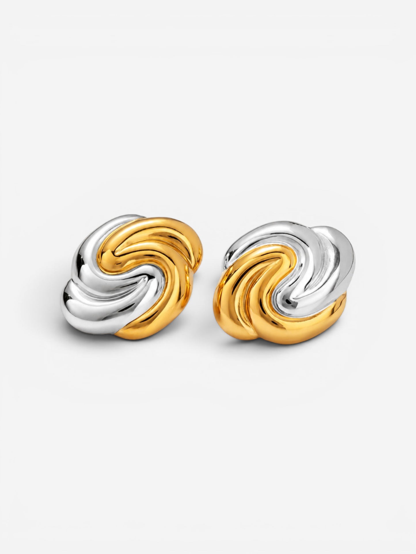 Gold and silver two-tone swirl earrings on white background