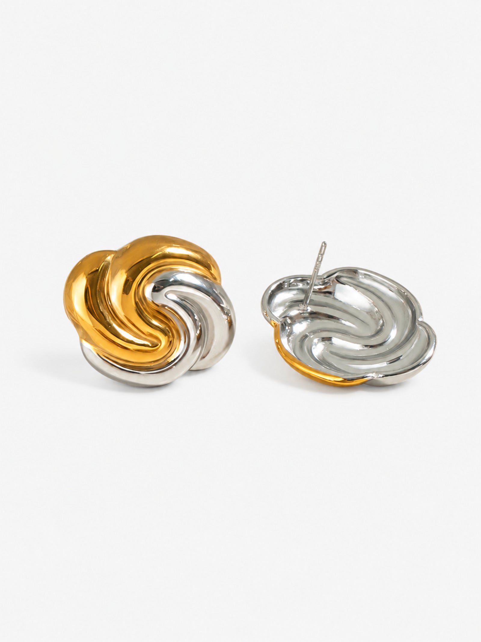 Close-up detail of two-tone swirl earrings with polished gold and silver finish