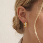 Close up of woman wearing gold Vega chunky hoop earrings with vertical crystal stripe detail.