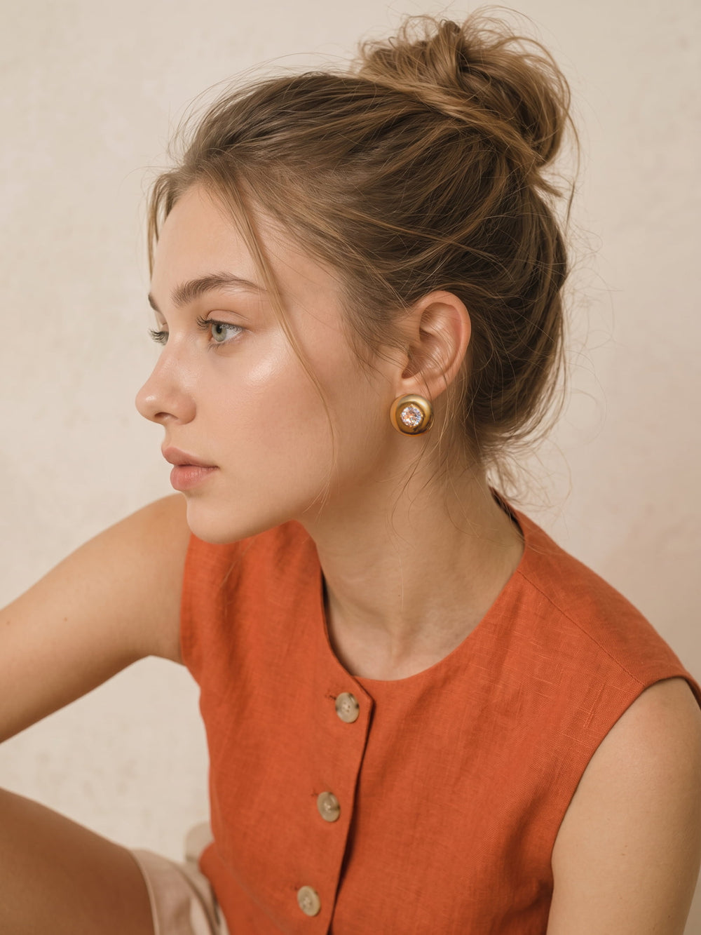 Close-up of Vesta Bold Dome Studs worn on the ear with a polished gold dome and clear cubic zirconia center