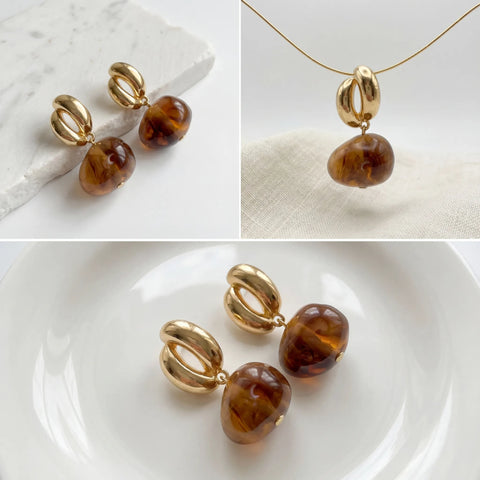 Aesthetic flat lay details of amber resin earrings and gold link design.