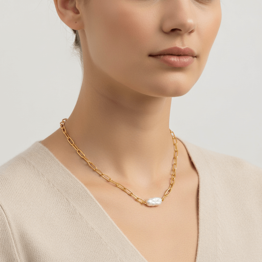 A model wearing The Aphrodite Necklace with a simple beige top, showcasing how the single pearl sits elegantly on the collarbone for a minimalist look.