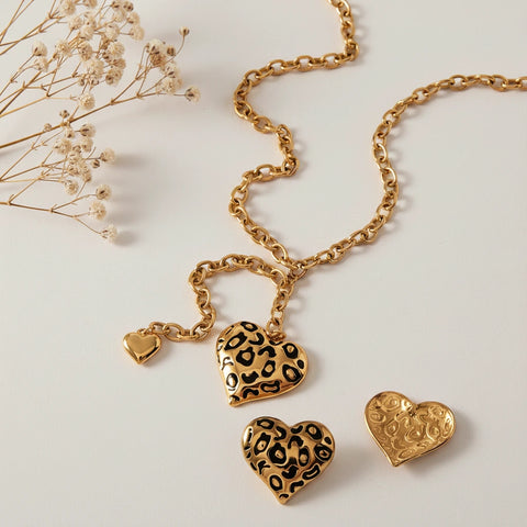 The Artemis leopard print heart necklace and matching earrings laid out to show their details, perfect for a bold, rock and roll style.
