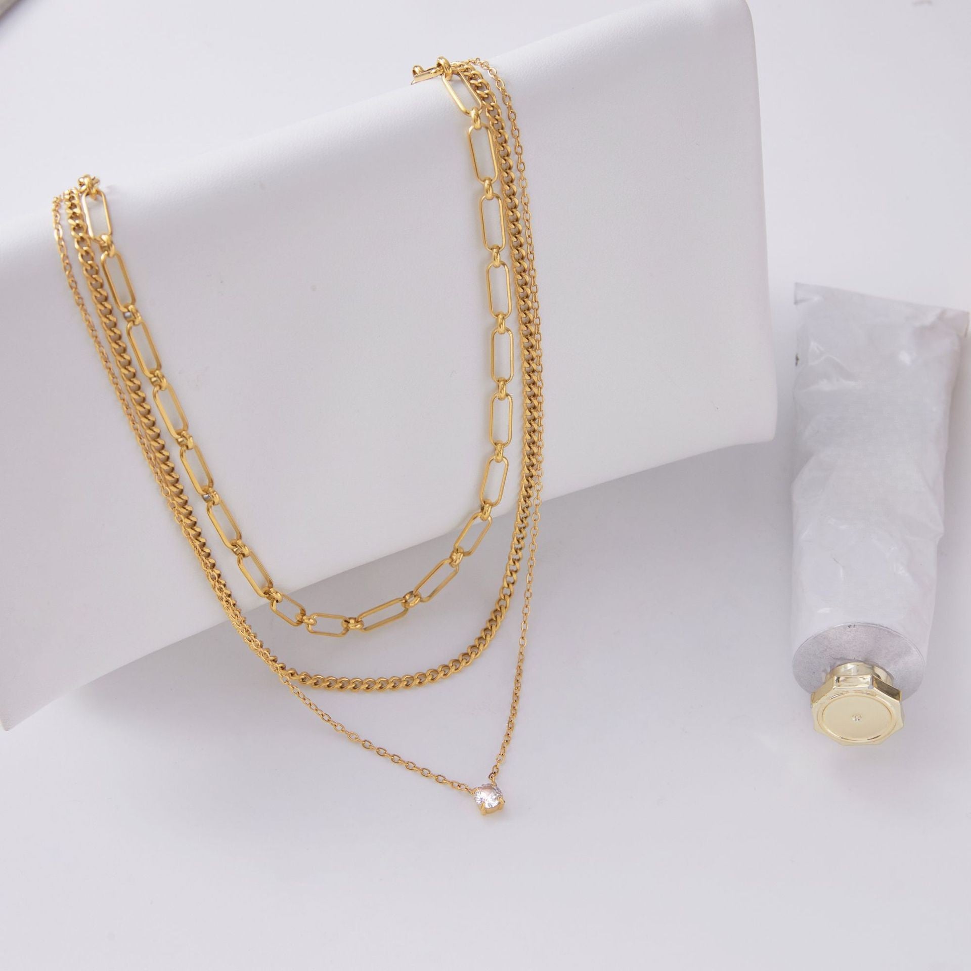 An artistic flat lay of The Charites Necklace styled with a modern lipstick, illustrating it as an essential accessory for everyday glamour.