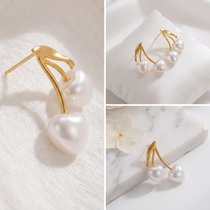 Aesthetic product photography details of pearl cherry earrings on white stone background.