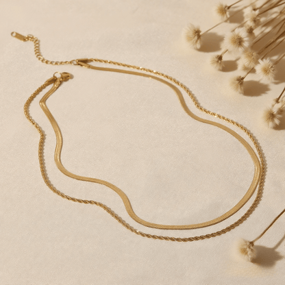 Classic Layered Chain Necklace — dual gold chains (herringbone + rope) on model neckline, elegant layering jewelry piece.