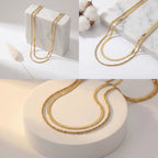 Aesthetic product photography of double strand gold necklace on white stone display.