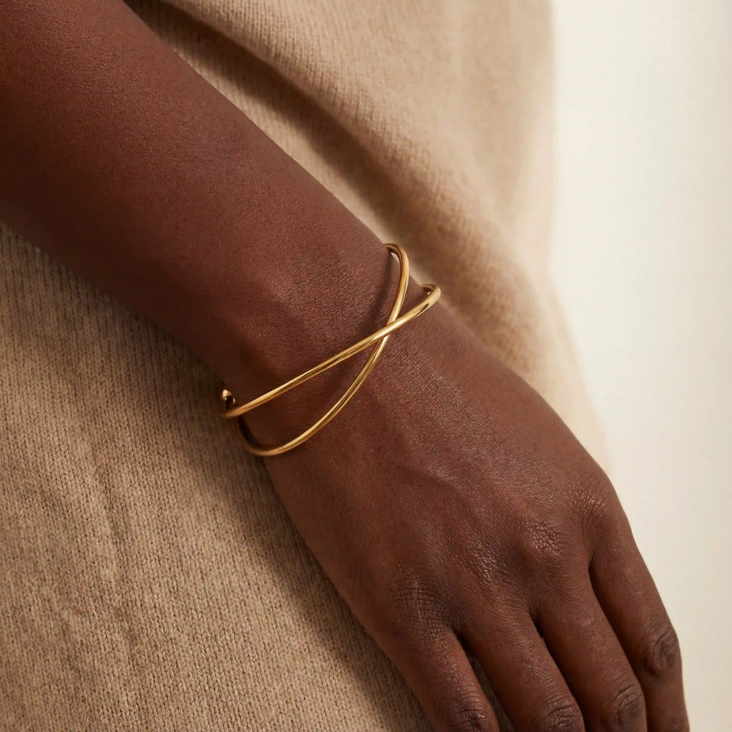 Black woman wearing minimalist gold wire cuff bracelet on wrist.