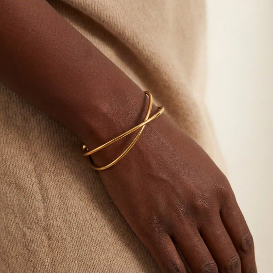Black woman wearing minimalist gold wire cuff bracelet on wrist.