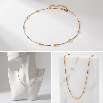 Aesthetic product photography of dainty gold beaded necklace on jewelry bust.