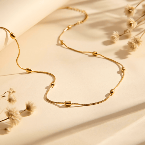 Extreme close-up macro shot of the delicate gold beads on the chain, highlighting texture and craftsmanship.