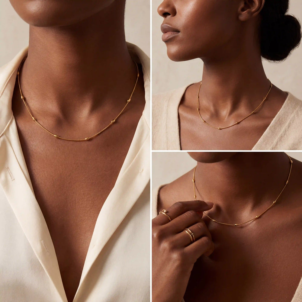 Model with dark skin styling minimalist gold beaded chain necklace layering essential.