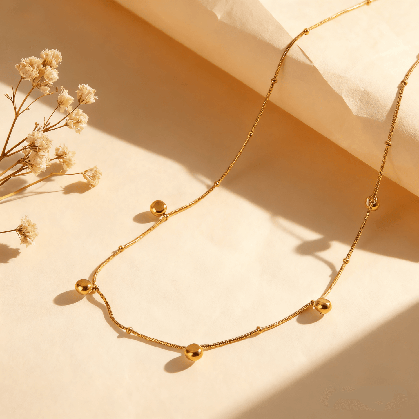 Close-up, macro shot of the smooth, reflective gold drop pendant on a delicate chain.