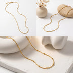 Aesthetic product photography of gold dotted bead necklace draped on white stone decor.
