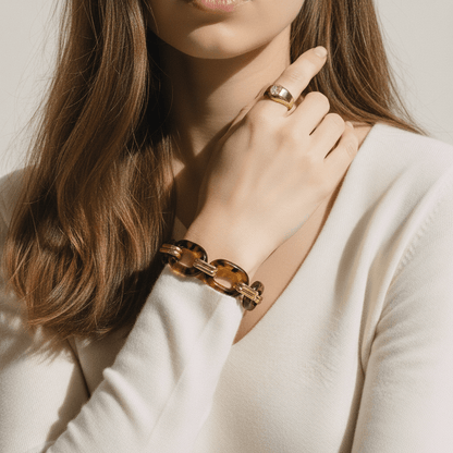 A woman wearing the Florence statement bracelet brings her hand to her chin in an elegant pose, showing how the piece complements a classic, minimal outfit.