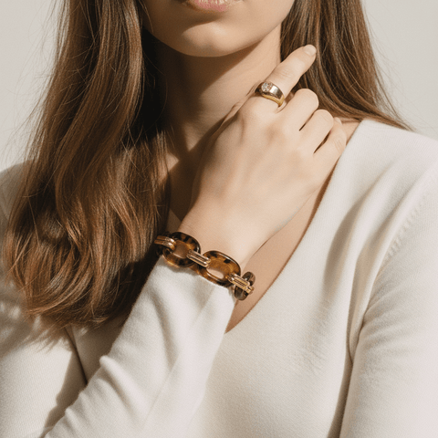 A woman wearing the Florence statement bracelet brings her hand to her chin in an elegant pose, showing how the piece complements a classic, minimal outfit.