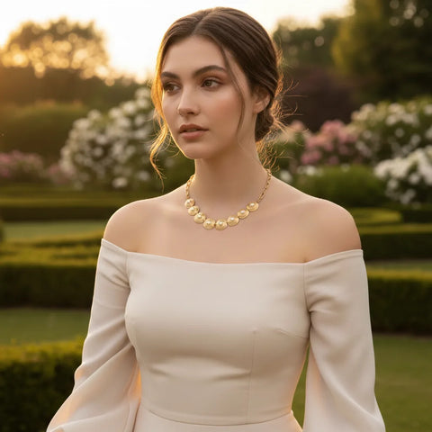 A model in a romantic garden at sunset, wearing The Hera Necklace with an off-the-shoulder gown, illustrating it as the perfect piece for a wedding or gala.