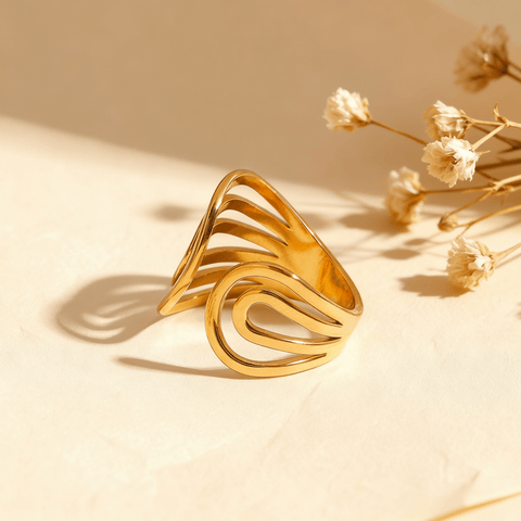 The Liquid Gold Ring in 18k gold plate on a beige background. The image details its abstract swirl design and open cuff, with annotations for its dimensions (1.87cm width), weight (3.7g), and materials (Waterproof, Hypoallergenic Stainless Steel).