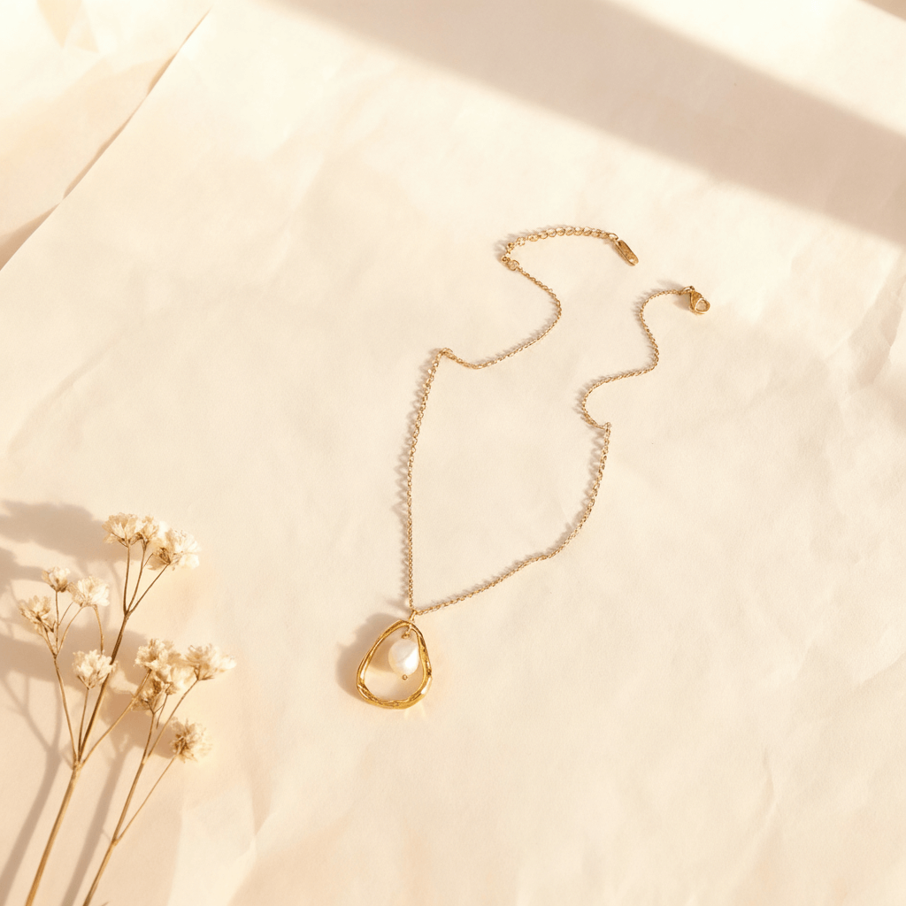 A macro shot of the single freshwater pearl from The Luna Pearl necklace, positioned to catch soft, natural light. The image captures the subtle, iridescent orient and the soft, moon-like glow of the pearl's surface.