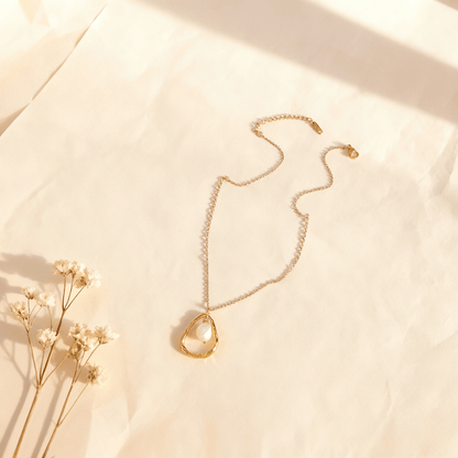 A macro shot of the single freshwater pearl from The Luna Pearl necklace, positioned to catch soft, natural light. The image captures the subtle, iridescent orient and the soft, moon-like glow of the pearl's surface.