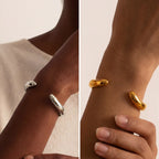 Model with dark skin styling gold and silver wave cuffs minimalist statement jewelry.