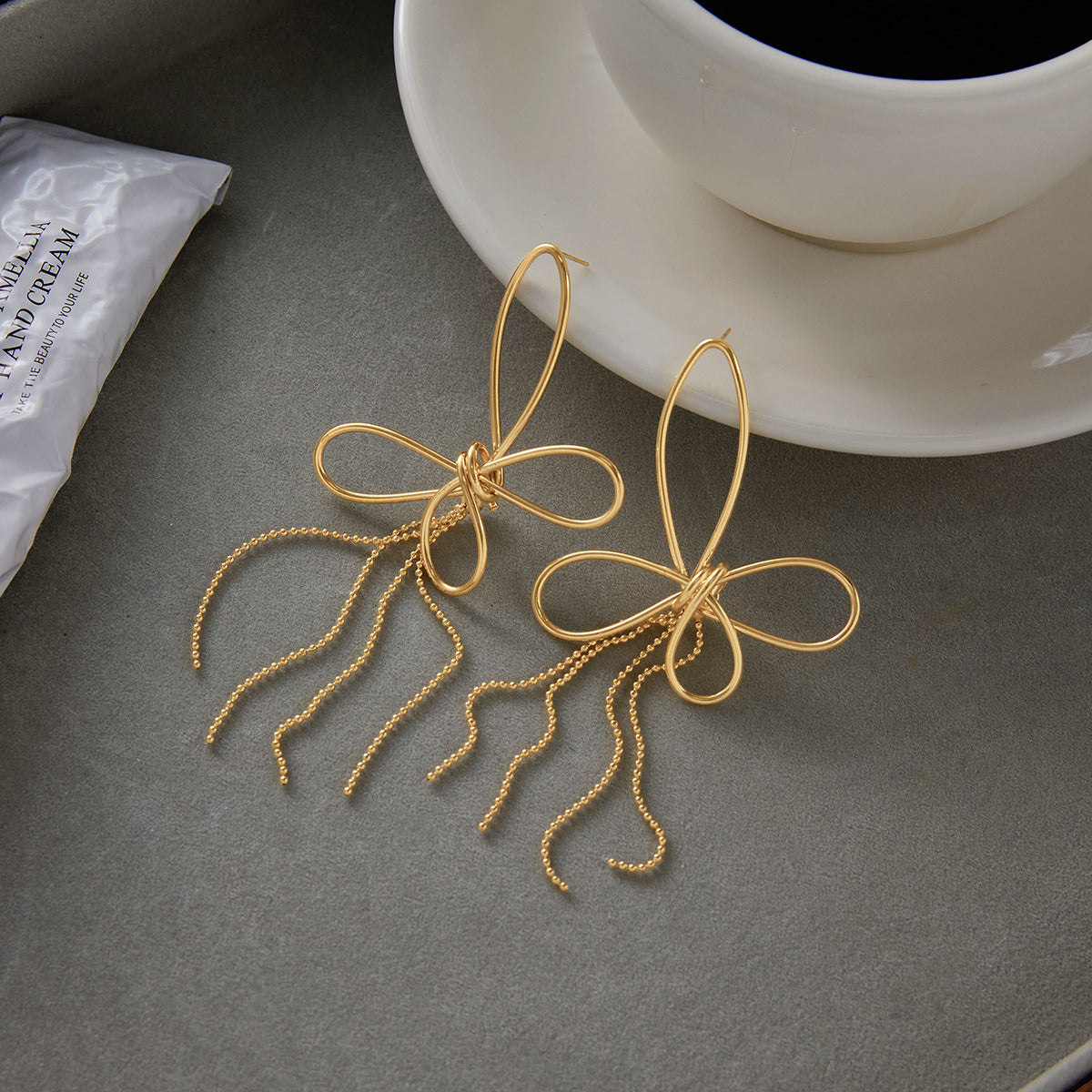 The Psyche Earrings styled next to a cup of coffee, illustrating them as the perfect, chic accessory for an everyday, sophisticated cafe look.