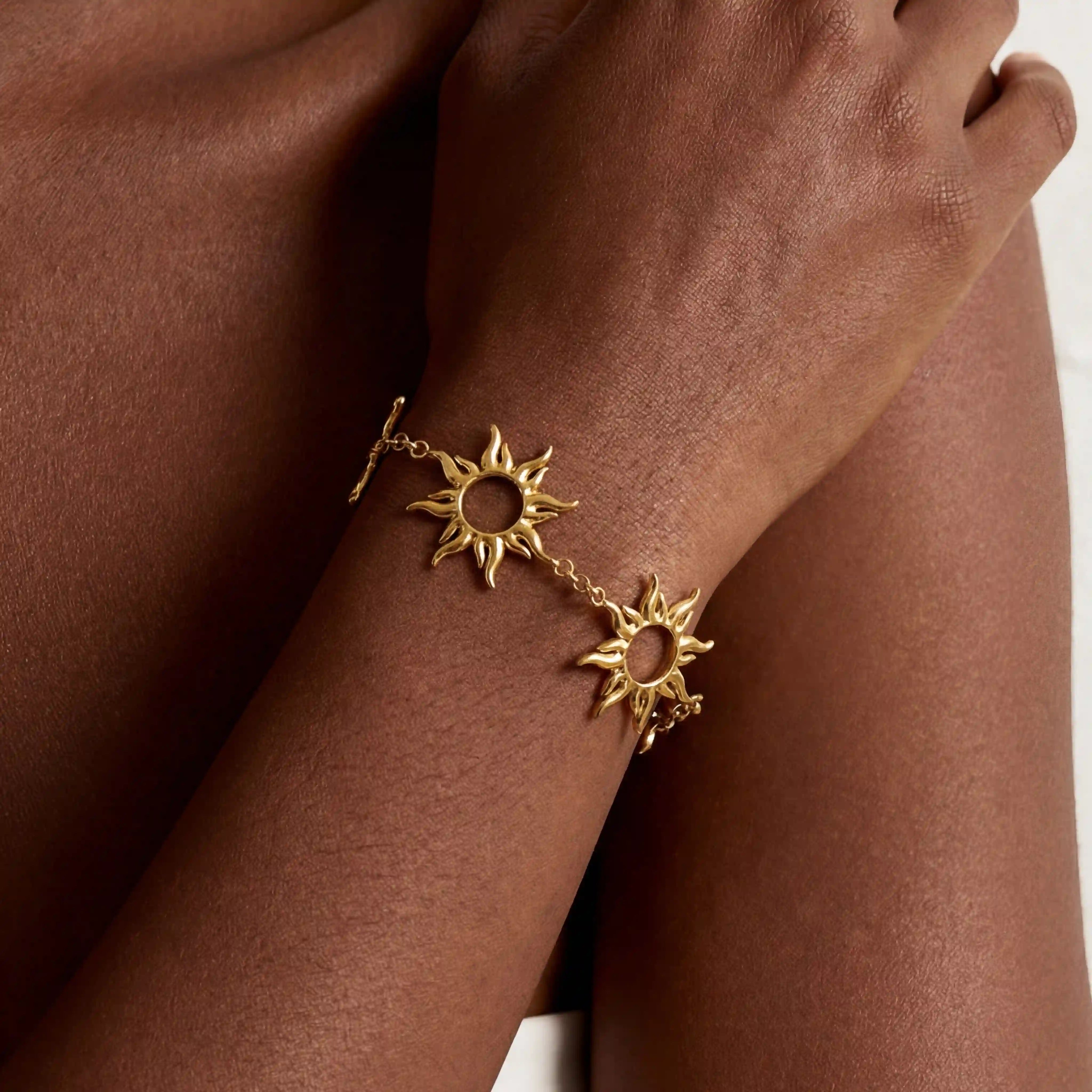 Close up of dark skin model wearing gold radiant sun charm bracelet celestial jewelry. Main image