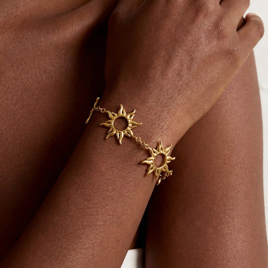 Close up of dark skin model wearing gold radiant sun charm bracelet celestial jewelry.