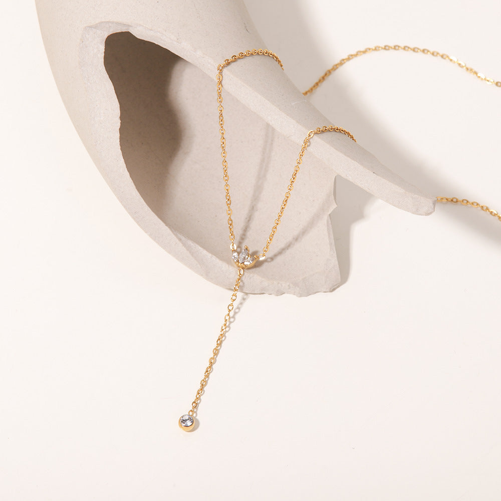 An artistic flat lay of The Reine Necklace on a white silk background with dramatic shadows, emphasizing its delicate sparkle and sophisticated Y-shape.