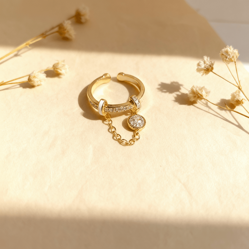 A macro close-up of the dangle charm on The Comet Ring. The image details the intricate pavé setting of the tiny cubic zirconia crystals on the disc, and the delicate links of the chain connecting it to the main band.