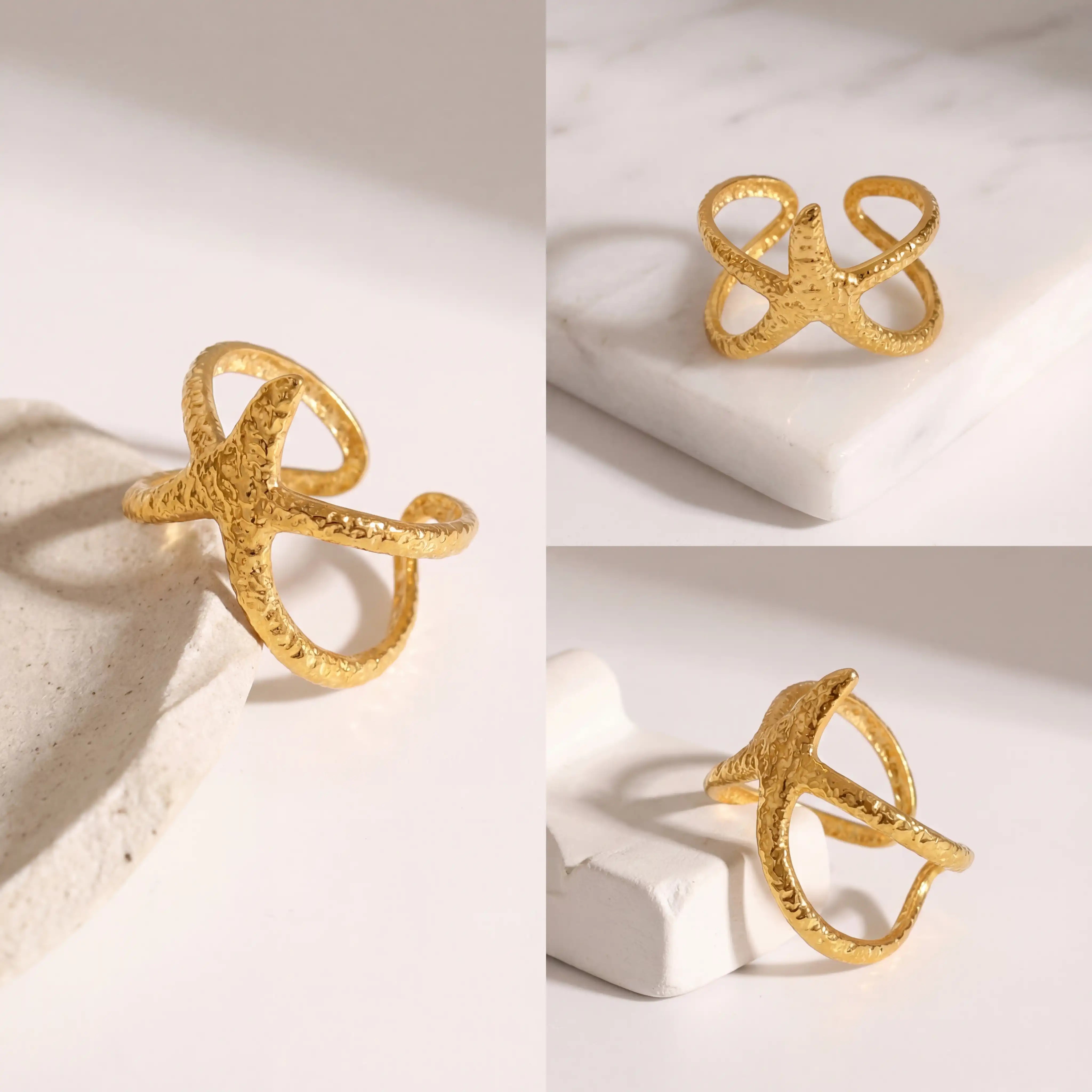 Aesthetic flat lay of sand textured gold starfish ring details on white stone.
