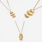 Aesthetic product photography of melted gold pebble necklace on white background.