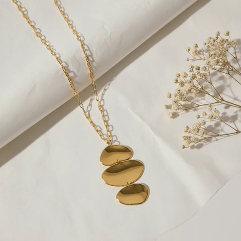 The Thalia Necklace styled on a rumpled white linen cloth with dried flowers, emphasizing its modern, sculptural, and artistic quality.