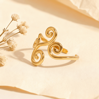 The Aphrodite Ring in 18k gold plate, a wide, adjustable open cuff ring with an intricate filigree design of vines and swirls. The image includes annotations for its dimensions, 1.9g weight, and materials (Waterproof, Hypoallergenic Stainless Steel).